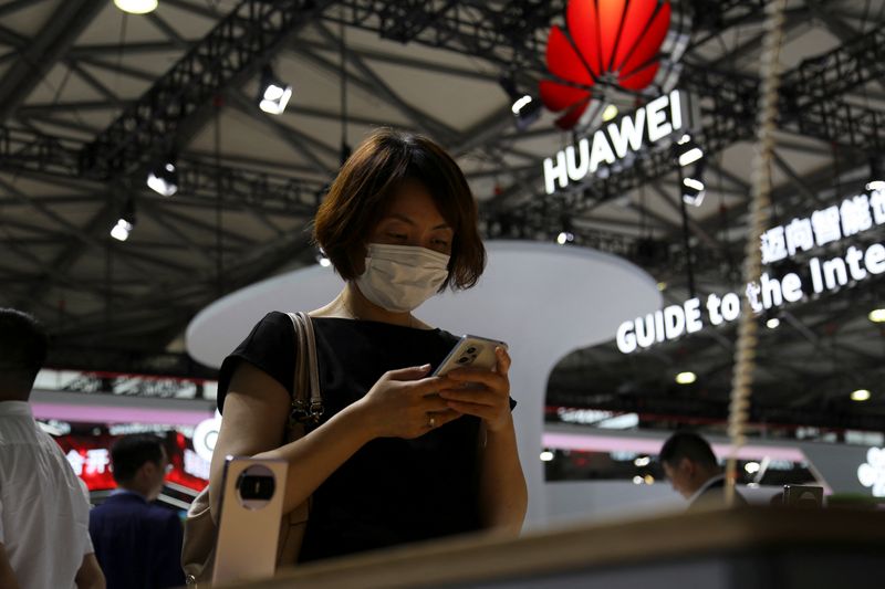 A visitor checks a mobile phone near the Huawei logo during the Mobile World Congress in Shanghai, China June 28, 2023. REUTERS/Nicoco Chan