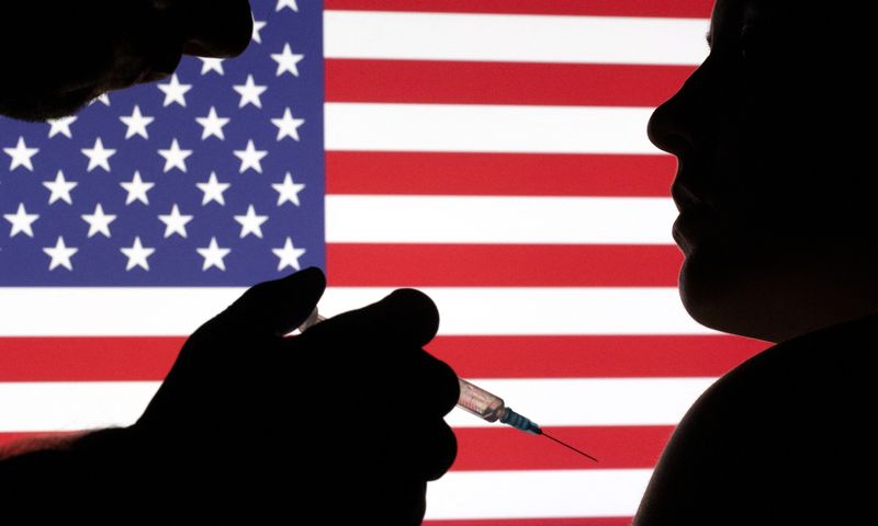 FILE PHOTO: People pose with syringe with needle in front of displayed U.S. flag in this illustration taken, December 11, 2021. REUTERS/Dado Ruvic/Illustration/File Photo