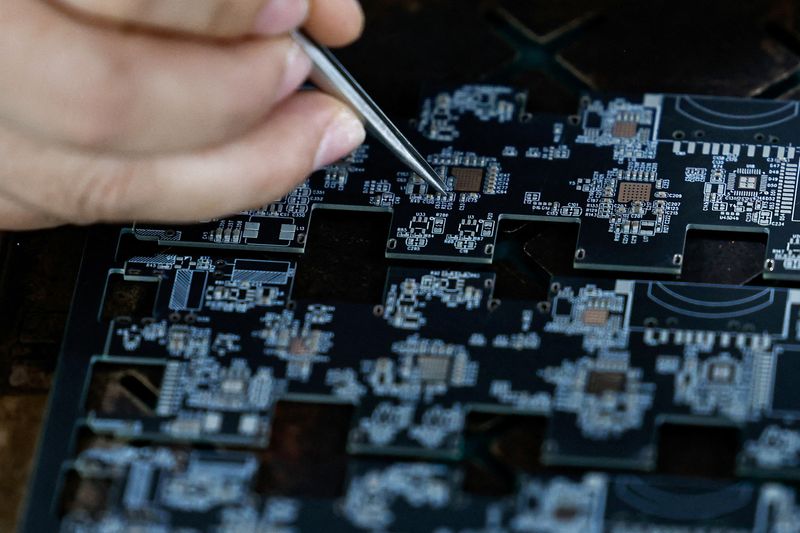 FILE PHOTO: An employee uses a pair of tweezers to adjust microchips and electronic components on a printed circuit board at a factory, which is in partnership with Agilian Technology, in Dongguan, Guangdong province, China March 16, 2026. REUTERS/Tingshu Wang/File Photo