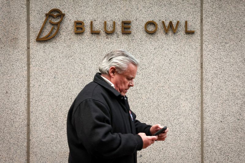 FILE PHOTO: A man walks past a logo for Blue Owl Capital on a midtown Manhattan office building in New York City, U.S., February 24, 2026.  REUTERS/Brendan McDermid/File Photo