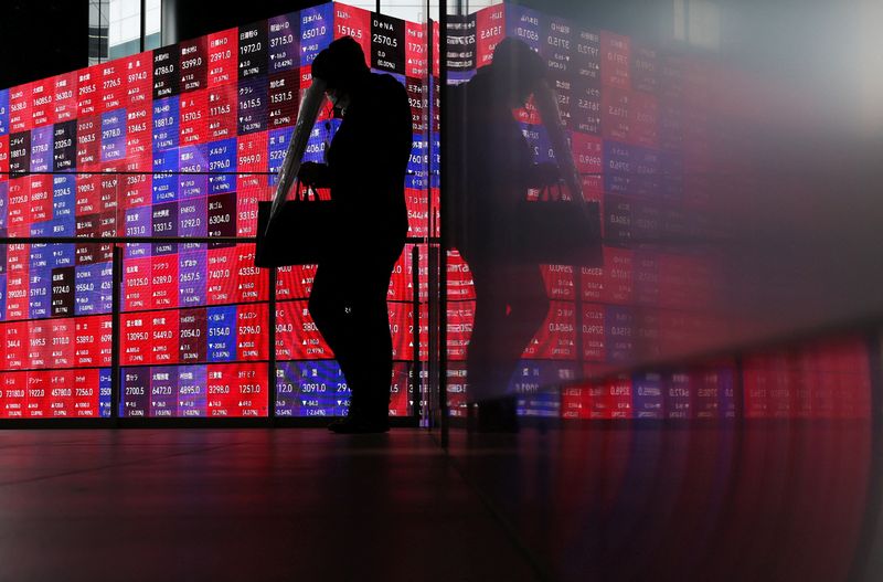 A man walks in front of an electronic screen displaying Japan's Nikkei stock prices quotation board inside a conference hall in Tokyo, Japan, April 27, 2026. REUTERS/Issei Kato