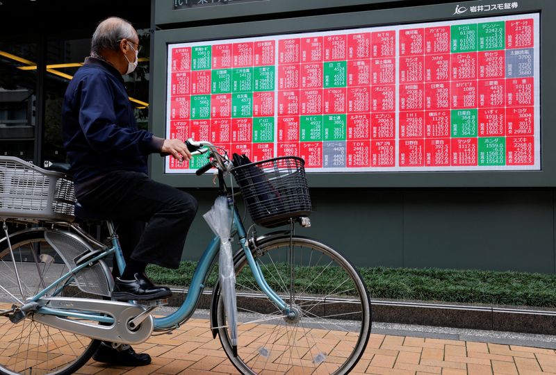 FILE PHOTO: A man looks at a stock quotation board displaying the Nikkei share average outside a brokerage in Tokyo, Japan, October 21, 2025. REUTERS/Manami Yamada/ File Photo