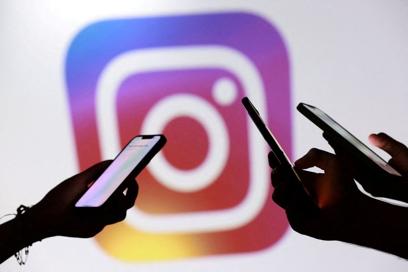 FILE PHOTO: Teenagers pose for a photo while holding smartphones in front of a Facebook logo in this illustration taken September 11, 2025. REUTERS/Dado Ruvic/Illustration/File Photo