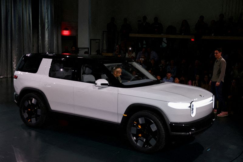 FILE PHOTO: Rivian CEO RJ Scaringe stands next to a R2 SUV at an unveiling event in Laguna Beach, California, U.S., March 7, 2024. REUTERS/Mike Blake/File Photo