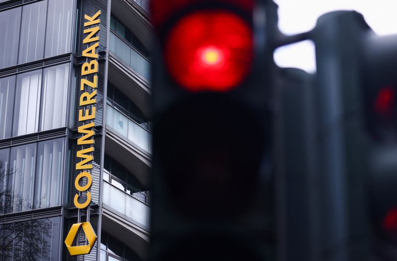 Traffic lights glow near a logo of Commerzbank at a branch in Cologne, Germany, March 16, 2026. REUTERS/Thilo Schmuelgen