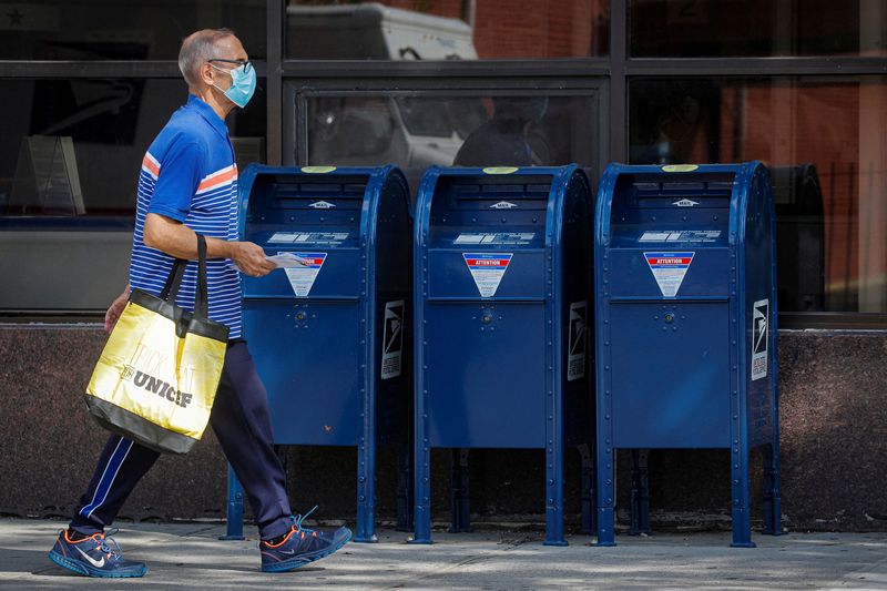 FILE PHOTO: A man carries letters into a United States Postal Service (USPS) post office in the Brooklyn borough of New York City, U.S., August 21, 2020. REUTERS/Brendan McDermid/File Photo