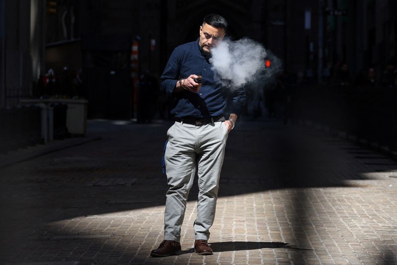 A man uses an e-cigarette on Wall Street outside the New York Stock Exchange (NYSE) in New York City, U.S., April 9, 2025. REUTERS/Kylie Cooper
