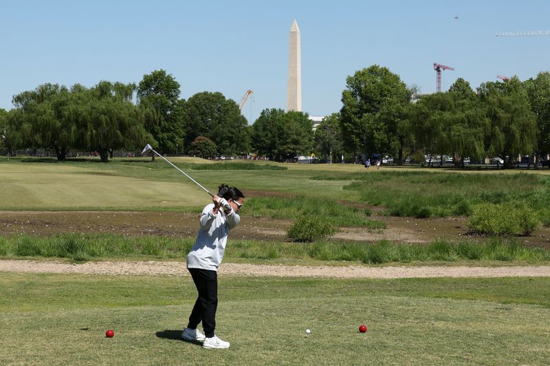 With the Washington Monument in the background, a golfer tees off at East Potomac Golf Course, whose future is in the courts as the Trump administration plans to take over operations and close it down to begin maintenance work, in Washington, D.C., U.S., May 4, 2026. REUTERS/Kevin Lamarque