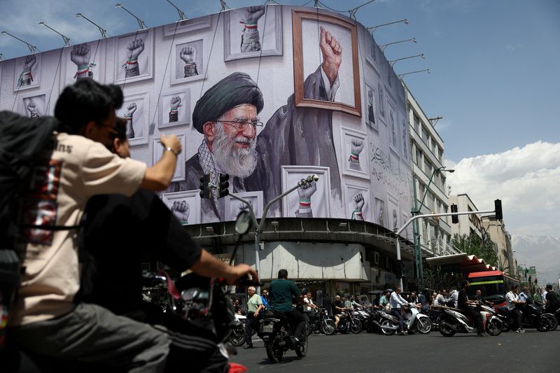People ride motorcycles near a billboard featuring an image of the late Supreme Leader of Iran, Ayatollah Ali Khamenei, in Tehran, Iran, May 6, 2026. Majid Asgaripour/WANA (West Asia News Agency) via REUTERS