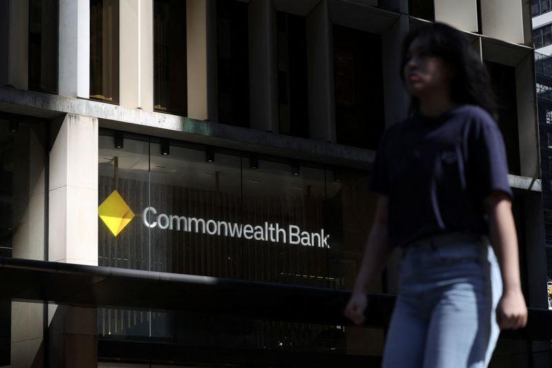 A woman walks past a Commonwealth Bank of Australia (CBA) logo displayed above a branch in Sydney, Australia, October 15, 2025. REUTERS/Hollie Adams