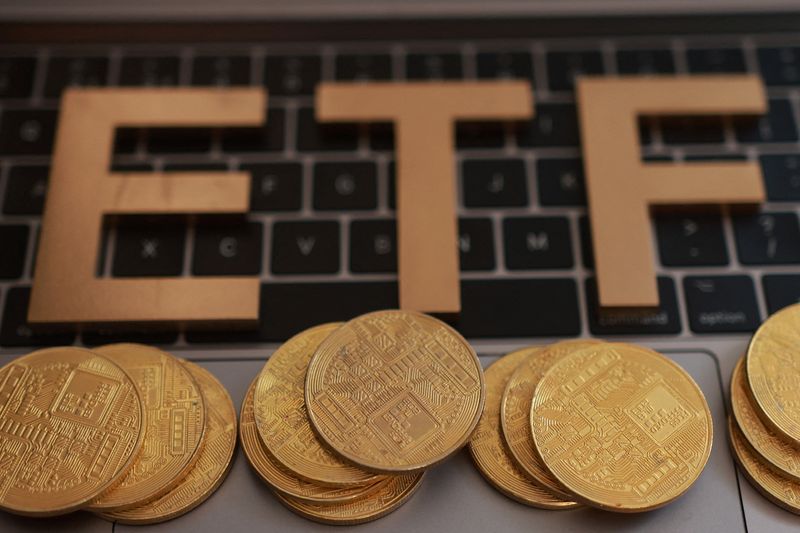 A 3D printed word "ETF (Exchange-Traded Fund)" and representations of cryptocurrencies are placed on a keyboard in this illustration taken October 16, 2025. REUTERS/Dado Ruvic/Illustration