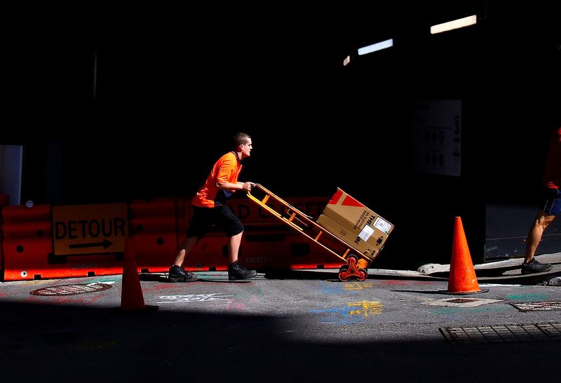 A worker pushes a trolley loaded with goods past a construction site in the central business district (CBD) of Sydney in Australia, March 15, 2018. REUTERS/David Gray