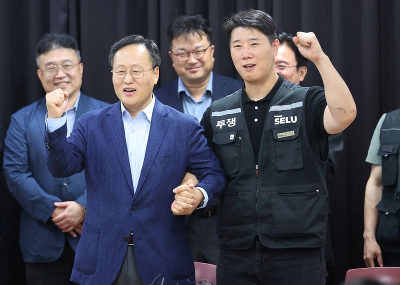 Choi Seung-ho, head of Samsung Electronics union and Yeo Myung-koo, head of the People Team under Samsung's Device Solutions division and the company's chief management negotiator, pose for photographs after reaching a tentative pay deal in Suwon, South Korea, May 20, 2026.   Yonhap via REUTERS
