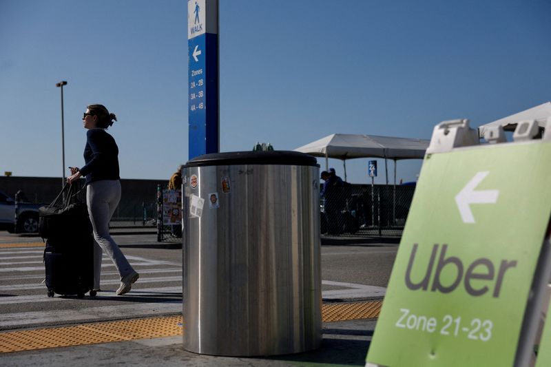 A traveler walks into the Uber pickup zone at the Los Angeles International Airport's LAX-it pick up terminal in Los Angeles, California, U.S., March 10, 2026.  REUTERS/Caroline Brehman
