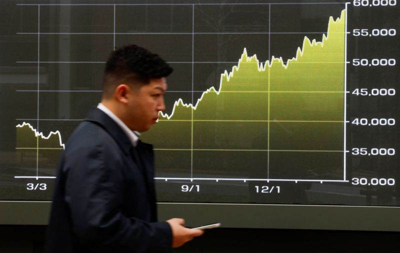 A man walks past a screen displaying a graph showing Japan's Nikkei share average within this year outside a brokerage in Tokyo, March 2, 2026. REUTERS/Manami Yamada