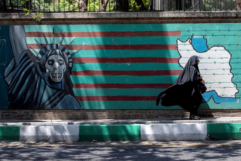 FILE PHOTO: A woman walks past the mural showing U.S. flag with barbed wire and the Statue Of Liberty with skull face in Tehran, Iran June 25, 2019.  Nazanin Tabatabaee/Nazanin Tabatabaee/West Asia News Agency via REUTERS/File Photo