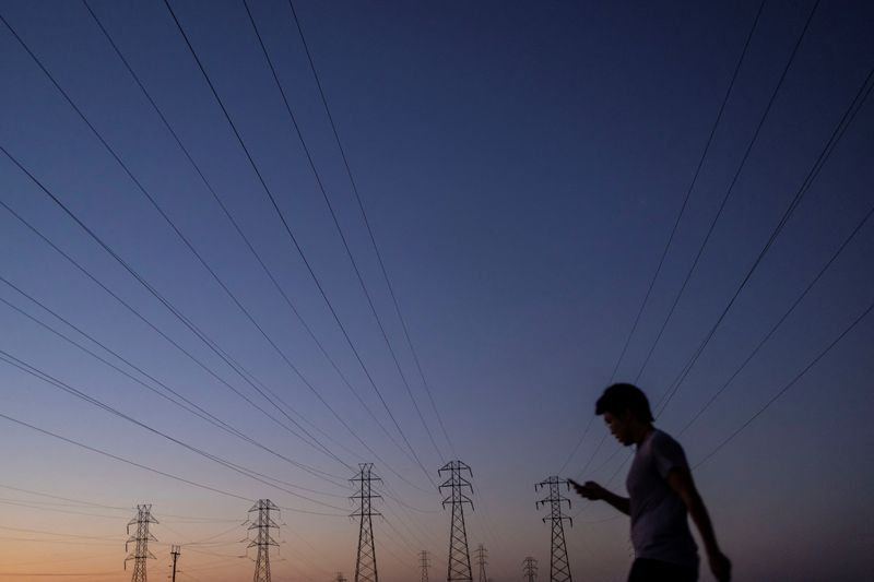 A man walks by power lines in Mountain View, California, U.S., August 17, 2022. REUTERS/Carlos Barria