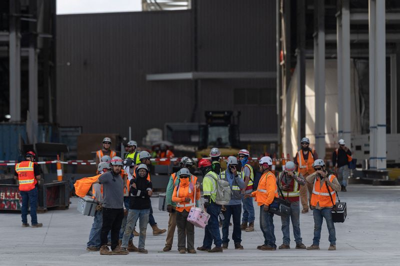 FILE PHOTO: Workers leave a SpaceX construction site as the company prepares to file for an initial public offering (IPO), in Starbase, Texas, U.S., April 22, 2026. REUTERS/Carlos Barria/File Photo