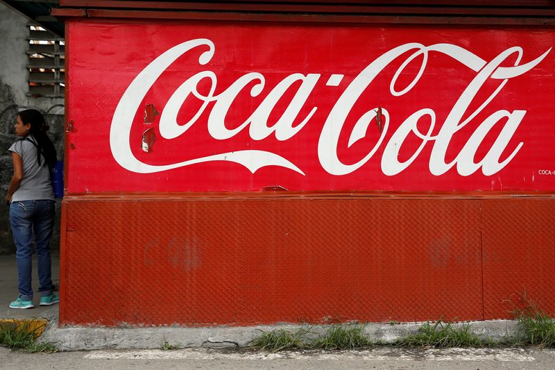 A woman stands next to the logo of Coca-Cola at a kiosk in Caracas, Venezuela May 24, 2016. REUTERS/Carlos Garcia Rawlins