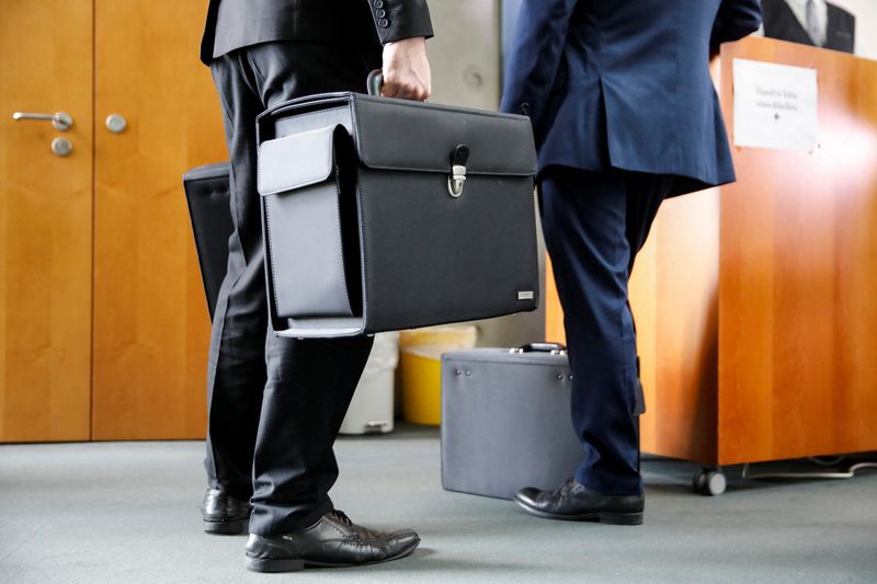 People with briefcases come out of a boardroom in this file photo dated July 29, 2020. REUTERS/Axel Schmidt