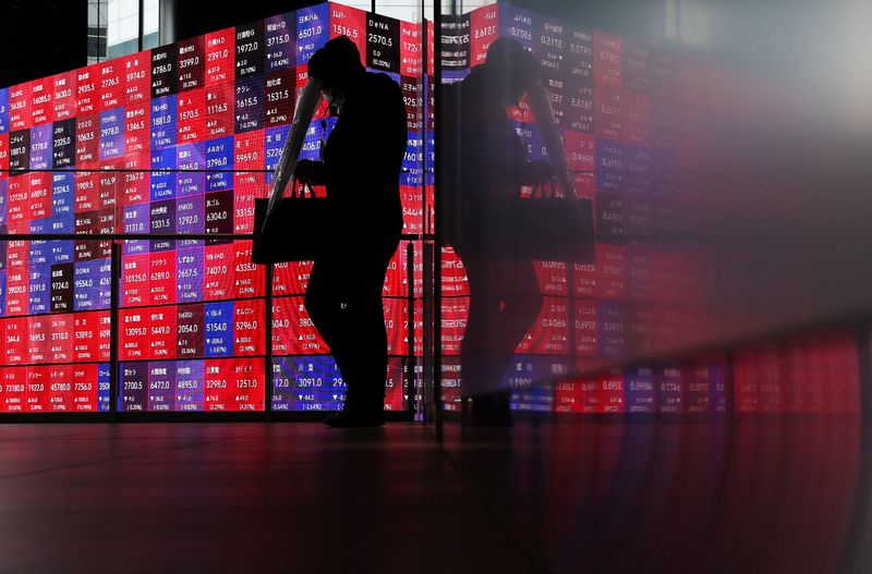 A man walks in front of an electronic screen displaying Japan's Nikkei stock prices quotation board inside a conference hall in Tokyo, Japan, April 27, 2026. REUTERS/Issei Kato