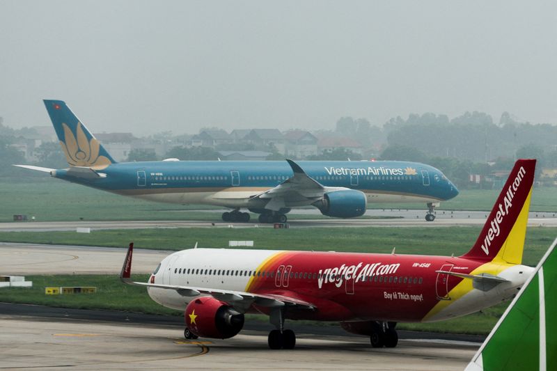 An airplane of VietJet Airline taxis in front of the national flag carrier Vietnam Airlines airplane, at Noi Bai International Airport, in Hanoi, Vietnam, May 28, 2025. REUTERS/Chalinee Thirasupa