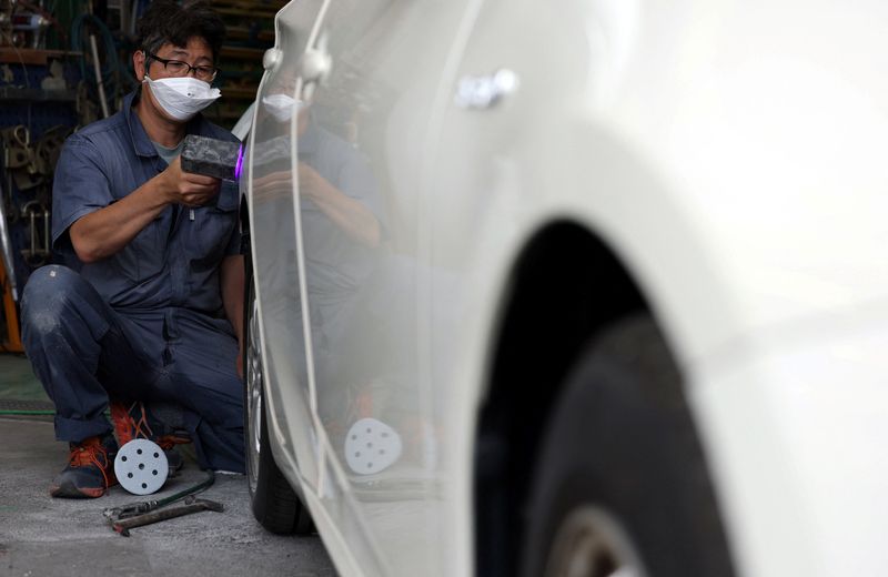 An employee of Fuchu Car, a repair shop that handles accident repairs as well as regular inspections, works on a "pearl white" body car at their workshop in Tokyo, Japan May 29, 2026. REUTERS/Issei Kato