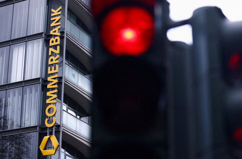 FILE PHOTO: Traffic lights glow near a logo of Commerzbank at a branch as Italy's UniCredit launches an unsolicited bid to increase its stake above 30% in Commerzbank, crossing the mandatory 30% takeover threshold under German law, in Cologne, Germany, March 16, 2026. REUTERS/Thilo Schmuelgen/File Photo