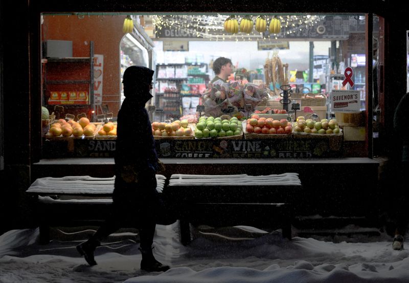 A pedestrian walks past a grocery store displaying fresh fruit during a winter snowstorm in Boston, Massachusetts, U.S., January 25, 2026.   REUTERS/Brian Snyder