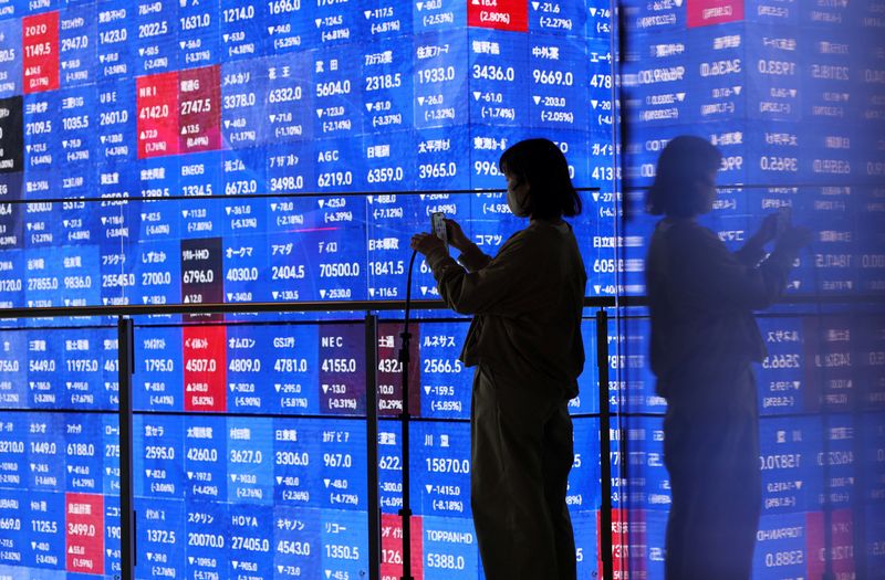 A visitor stands next to an electronic screen displaying Japan's Nikkei stock prices quotation board inside a conference hall in Tokyo, Japan March 4, 2026. REUTERS/Issei Kato