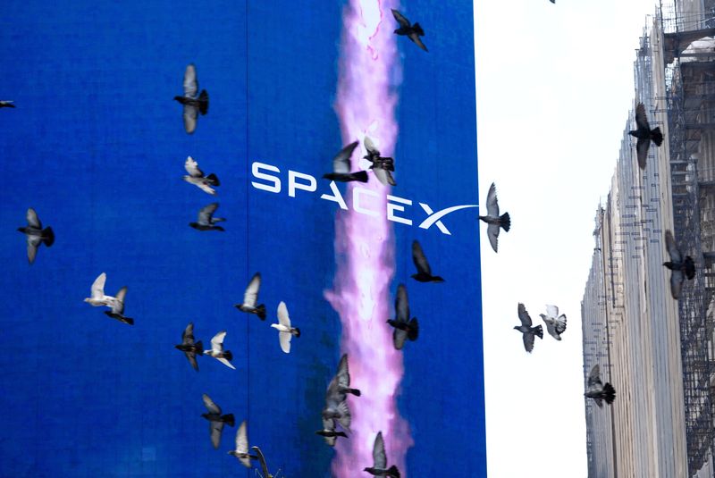 Birds fly past a SpaceX advertisement outside the Nasdaq MarketSite, on the day of SpaceX's initial public offering (IPO), in New York City, U.S., June 12, 2026. REUTERS/David Dee Delgado