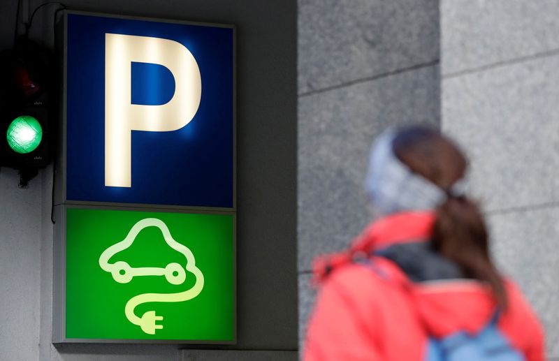 A woman walks past a sign of a charging point for electric vehicles in Prague, Czech Republic March 9, 2018. REUTERS/David W Cerny