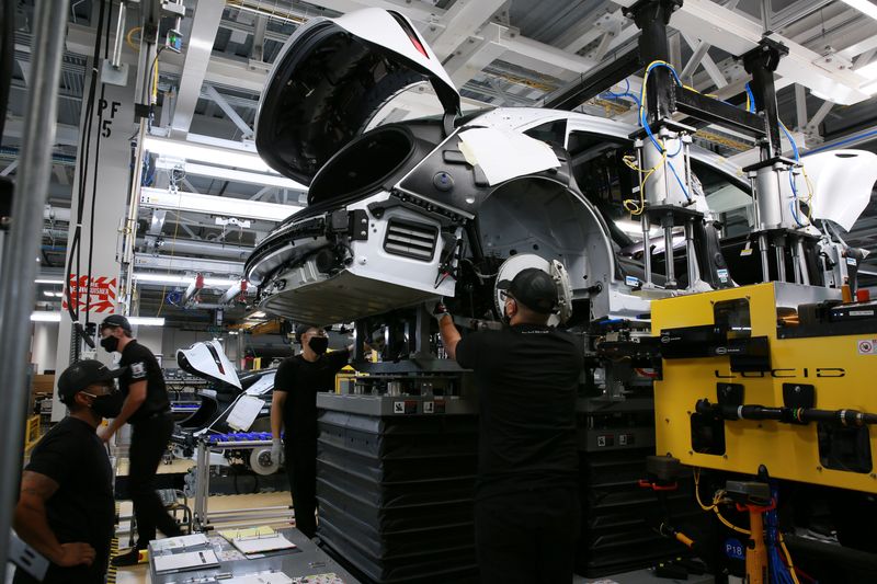Workers marry the body structure with the battery pack and the front and rear sub frames as they assemble electric vehicles at the Lucid Motors plant in Casa Grande, Arizona, U.S. September 28, 2021.  REUTERS/Caitlin O'Hara