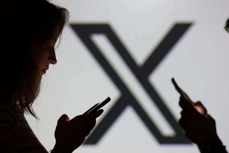 Teenagers pose for a photo while holding smartphones in front of a X logo in this illustration taken September 11, 2025. REUTERS/Dado Ruvic/Illustration