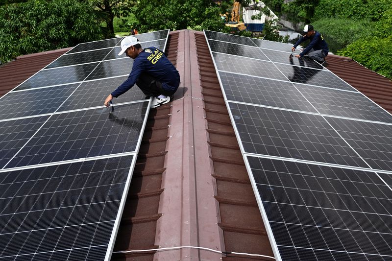 Workers install solar panels on the roof of a house in Kawit, Philippines, June 26, 2026. REUTERS/Noel Celis