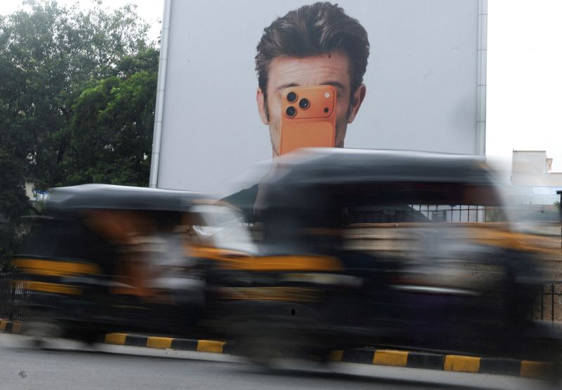 Auto rickshaws move past an Apple iPhone hoarding on a street in Mumbai, India, June 29, 2026. REUTERS/Francis Mascarenhas
