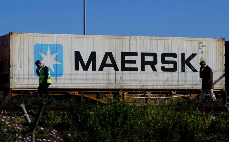 Workers talk on their mobile phones, as a Maersk container is transported by a train, near a port of Barcelona, Spain April 26, 2024. REUTERS/Nacho Doce