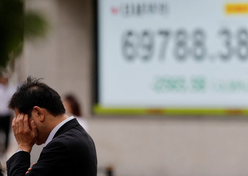 A pedestrian stands in front of a stock quotation board showing the Nikkei share average outside a brokerage in Tokyo, Japan, June 23, 2026.   REUTERS/Kim Kyung-Hoon