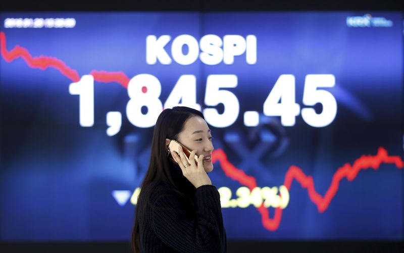 A woman talking on the phone walks past an electronic board of the Korea Composite Stock Price Index (KOSPI) at the Korea Exchange (KRX) in Seoul, South Korea, January 20, 2016  REUTERS/Kim Hong-Ji