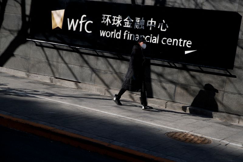A woman wearing a face mask walks past a financial center in the Central Business District following a nationwide outbreak of the novel coronavirus, in Beijing, China, February 22, 2020. REUTERS/Thomas Peter