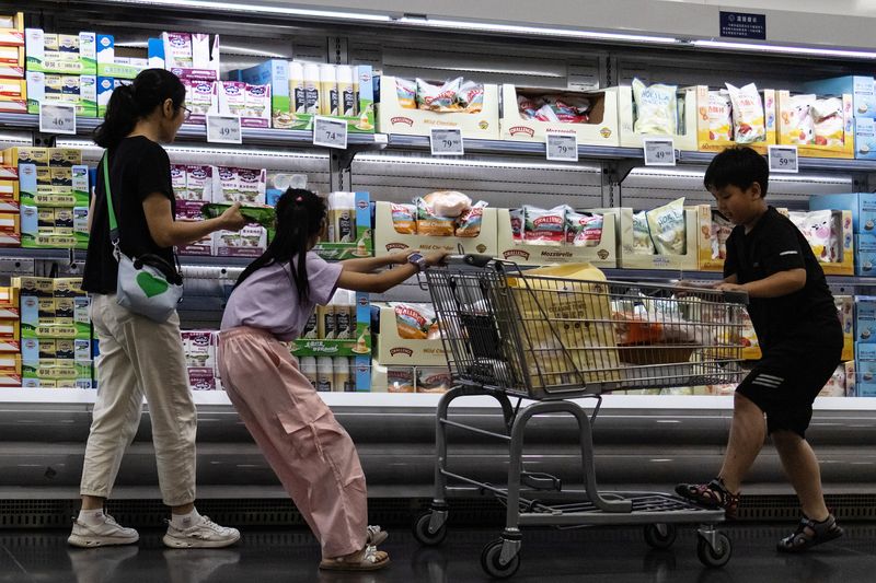A woman and two children shop in front of a refrigerated cheese shelf at a supermarket in Beijing, China, July 10, 2026. REUTERS/Maxim Shemetov