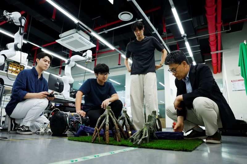 Park Shinwoo, PhD student of Civil and Environmental Engineering at the Korea Advanced Institute of Science and Technology (KAIST), Kim Nam Gyun, a postdoctoral researcher at KAIST and a soft robotics engineer, Hwang Jae Yun, a graduate student of Civil and Environmental Engineering at KAIST, and Ryu Jee-Hwan, a professor of civil and environmental engineering at KAIST, demonstrate a soft-growing robot as it extends between model tree branches at KAIST in Daejeon, South Korea, July 14, 2026. REUTERS/Kim Soo-hyeon
