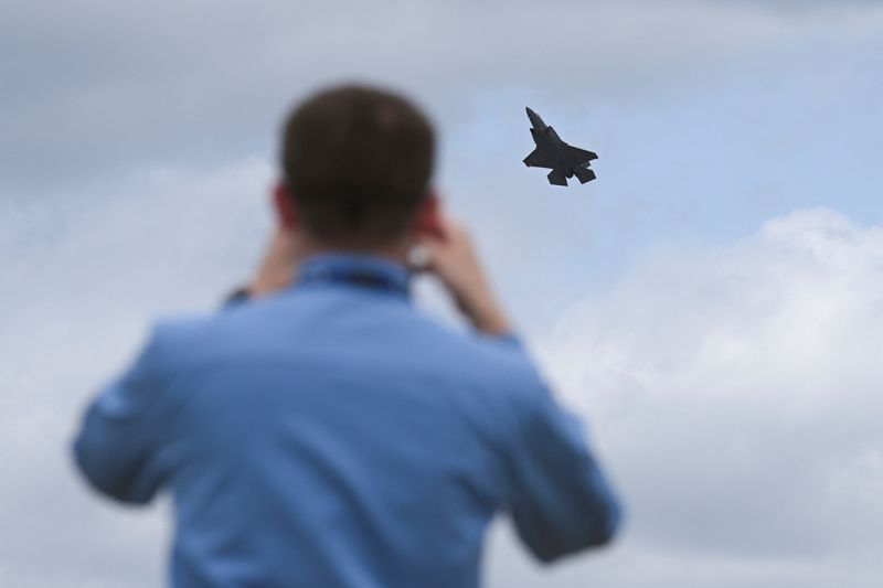 An attendee uses his phone as a Lockheed Martin F-35A flies at the Farnborough Airshow, in Farnborough, Britain, July 21, 2026. REUTERS/Jaimi Joy