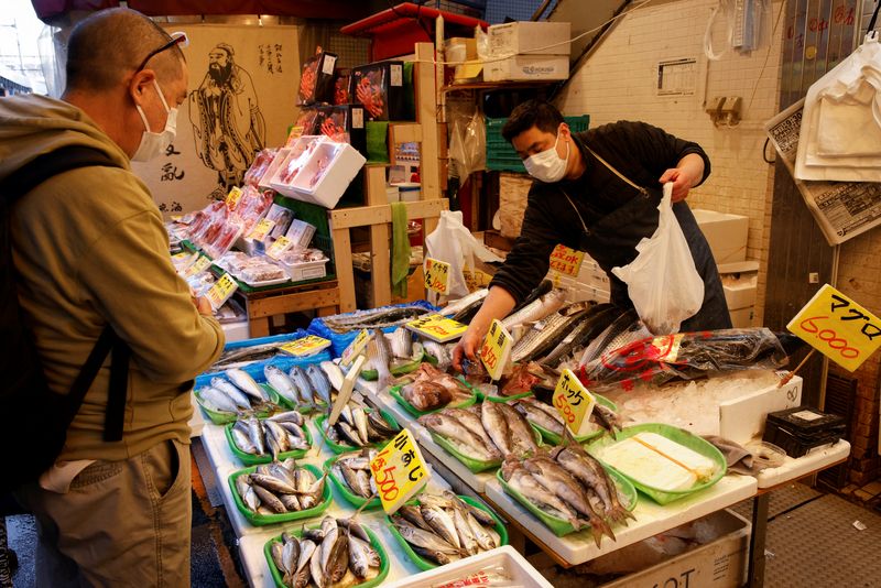 A man buys fish at a market in Tokyo, Japan March 3, 2023. REUTERS/Androniki Christodoulou