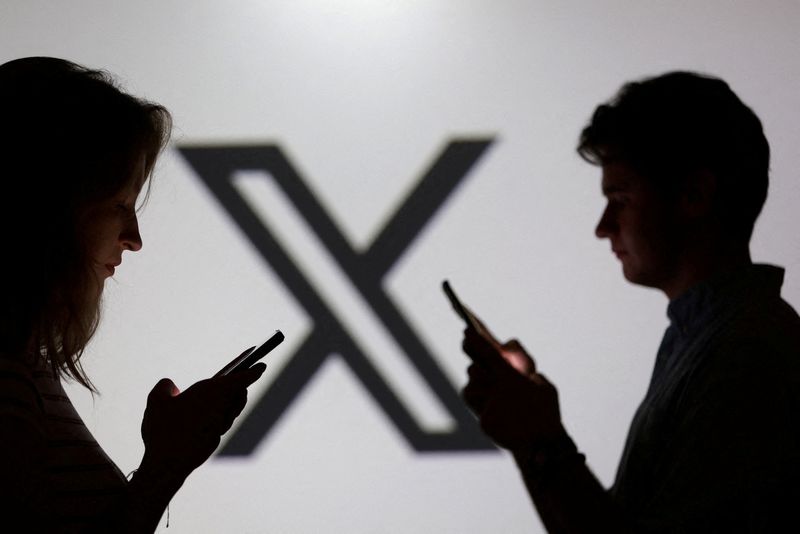 FILE PHOTO: Teenagers pose for a photo while holding smartphones in front of a X logo in this illustration taken September 11, 2025. REUTERS/Dado Ruvic/Illustration/File Photo