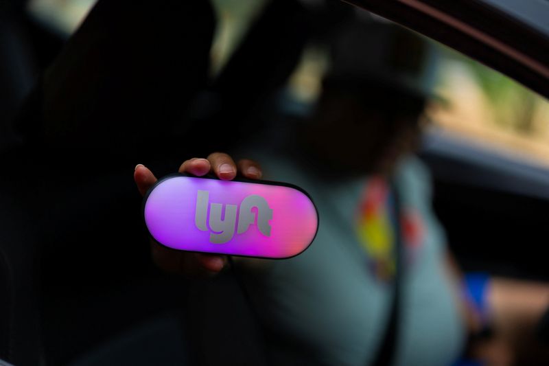 A Lyft driver holds up his Lyft sign as he picks up a customer at the airport in San Diego, California, U.S., May 12, 2026.  REUTERS/Mike Blake