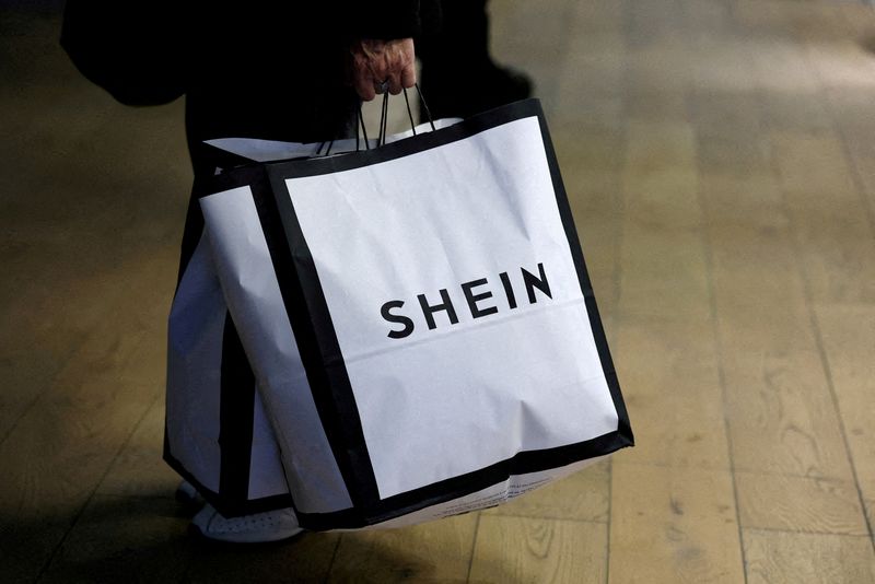 FILE PHOTO: FILE PHOTO: A customer holds shopping bags with a Shein logo in the first physical space of online fast-fashion retailer Shein on the day of its opening inside the Le BHV Marais department store, the Bazar de l'Hotel de Ville, in Paris, France, November 5, 2025. REUTERS/Sarah Meyssonnier/File Photo/File Photo/File Photo