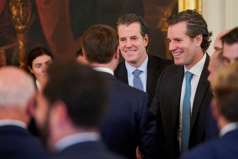 FILE PHOTO: Tyler Winklevoss and Cameron Winklevoss react on the day of U.S. President Donald Trump signs the "Genius Act", which will develop regulatory framework for stablecoin cryptocurrencies and expand oversight of the industry, at the White House in Washington, D.C., U.S., July 18, 2025. REUTERS/Nathan Howard/File Photo