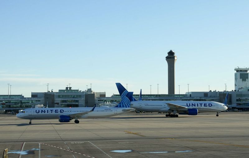 FILE PHOTO: The air traffic control tower is seen from the Denver International Airport terminal, as two United flights taxi away from the gate, in Denver, Colorado, U.S., May 15, 2025.  REUTERS/Megan Varner/File Photo