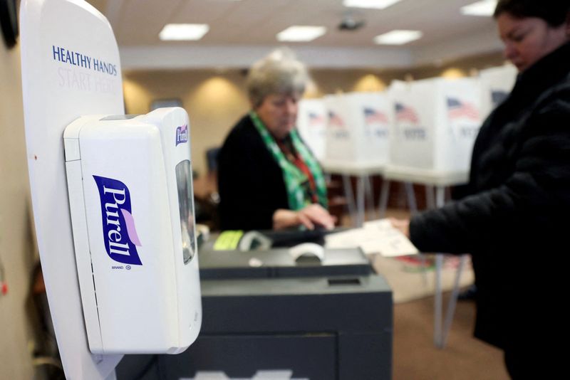 FILE PHOTO: A Purell brand hand sanitizer dispenser stands next to a ballot box at a polling station during the primary election in Utica, Illinois, U.S., March 17, 2020.  REUTERS/Daniel Acker/File Photo